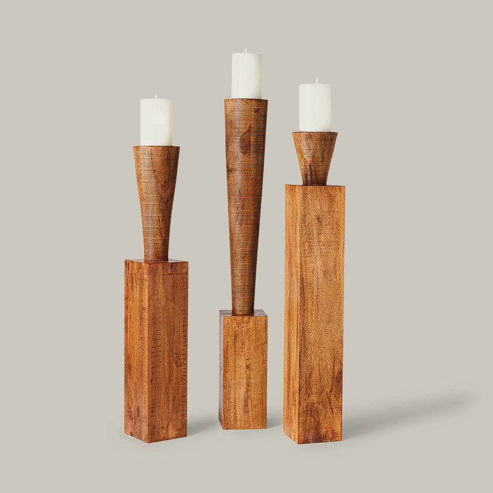 Lemieux et Cie Floor Pillar Candleholders, sculptural set with tapered forms and rectangular bases holding white pillar candles, shown on neutral backdrop.