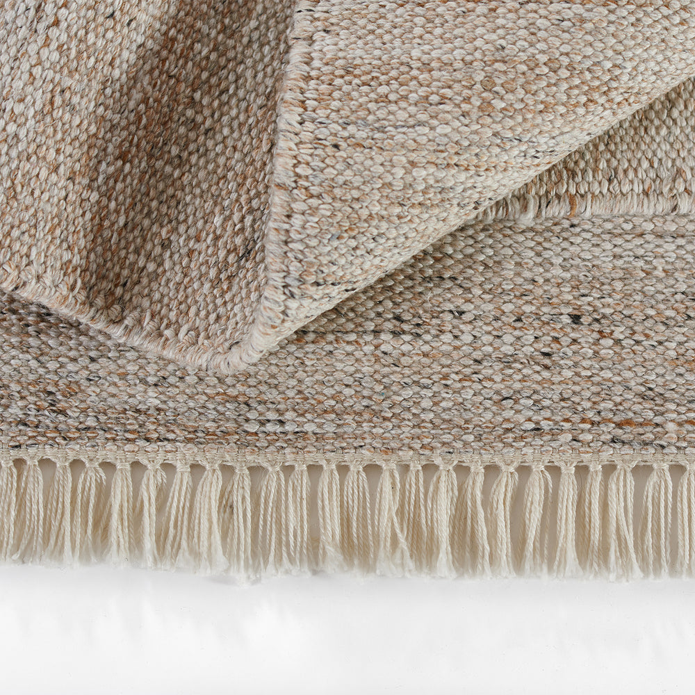 Lemieux et Cie Cove Chair in natural woven rug, handwoven textile with knotted fringe detail shown folded on white studio backdrop.