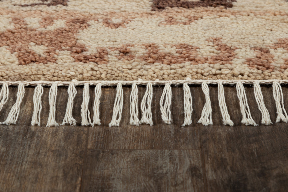 Lemieux et Cie Doukkala Carpet in ivory and mauve handknotted wool with hand-shorn texture, detail of fringed edge on dark wood floor.