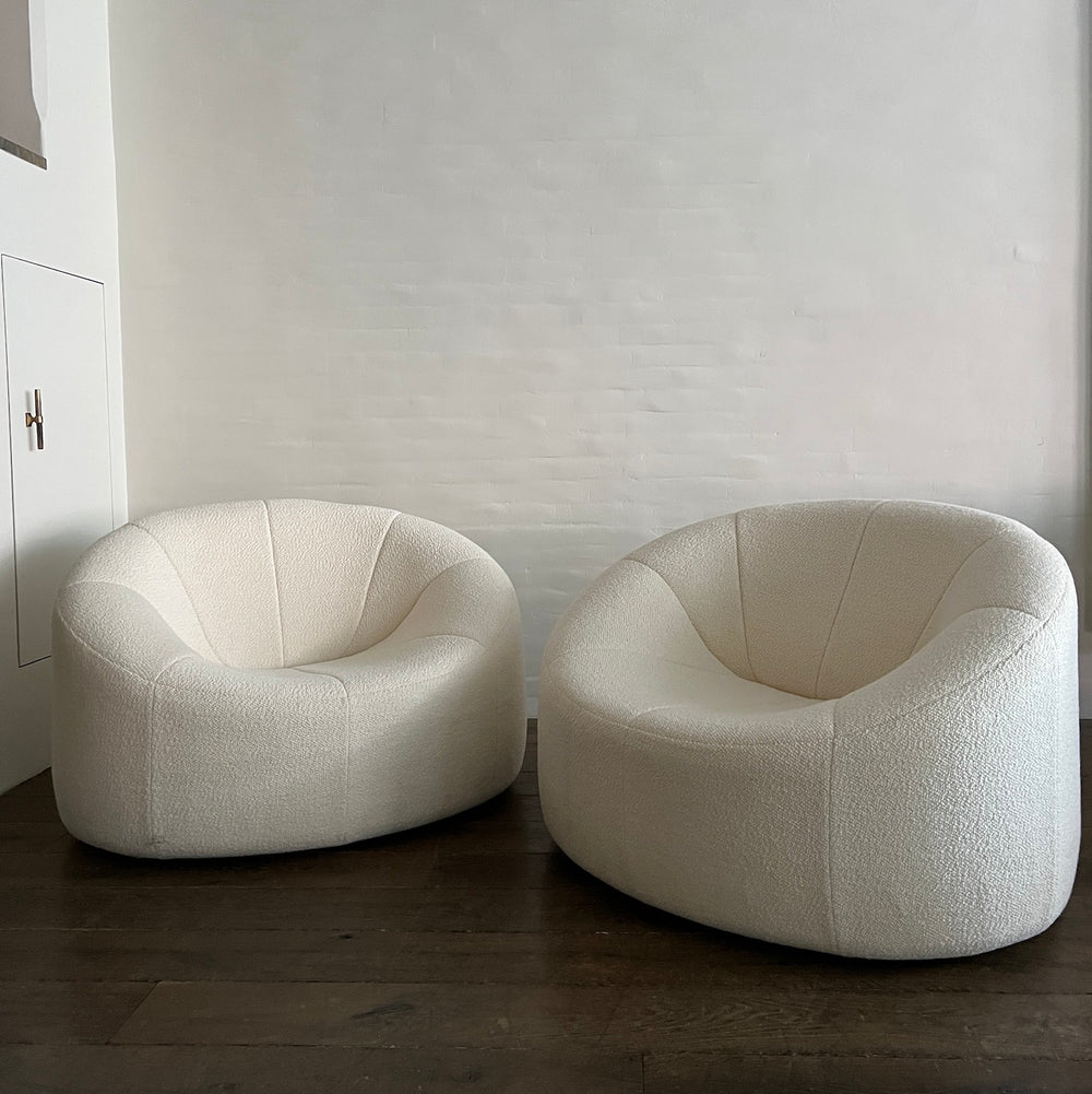 Lemieux et Cie swivel chair in light blush textured velvet, sculptural cup-shaped seat on memory-swivel base, pair shown on dark wood floors against neutral plaster walls.
