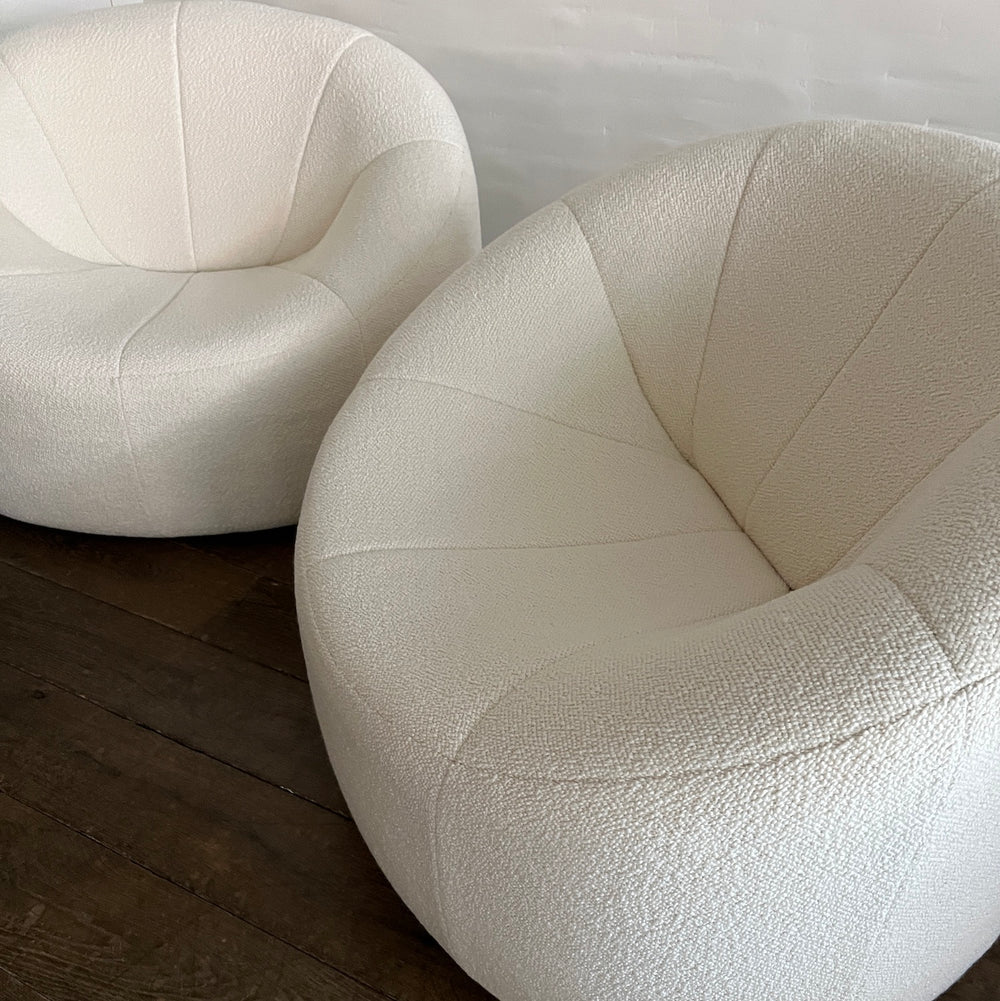 Lemieux et Cie sculptural swivel chairs in light blush textured velvet, cup-shaped seats with curved backs on dark wood flooring in soft daylight.