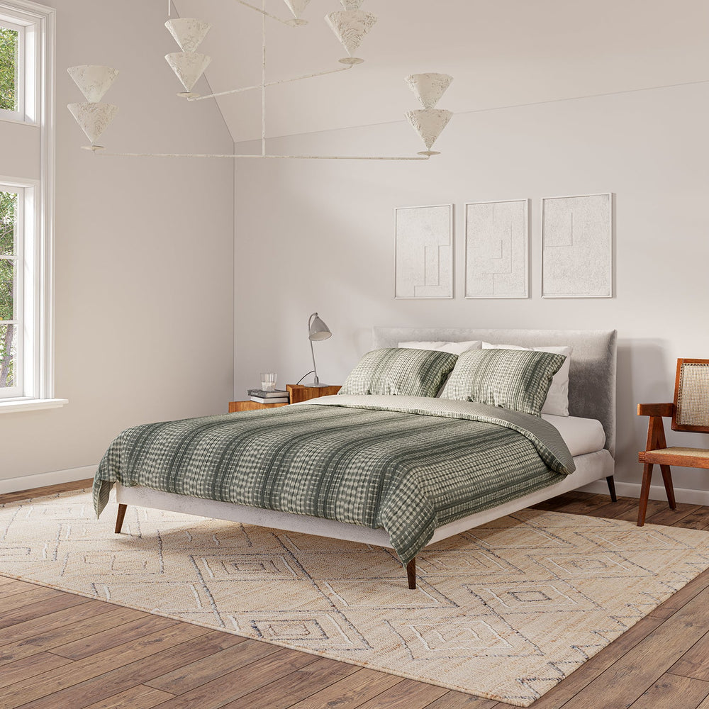 Lemieux et Cie Jepara Quilt Collection in cream cotton with geometric pattern, bedding styled in a neutral bedroom with wood floors and white walls