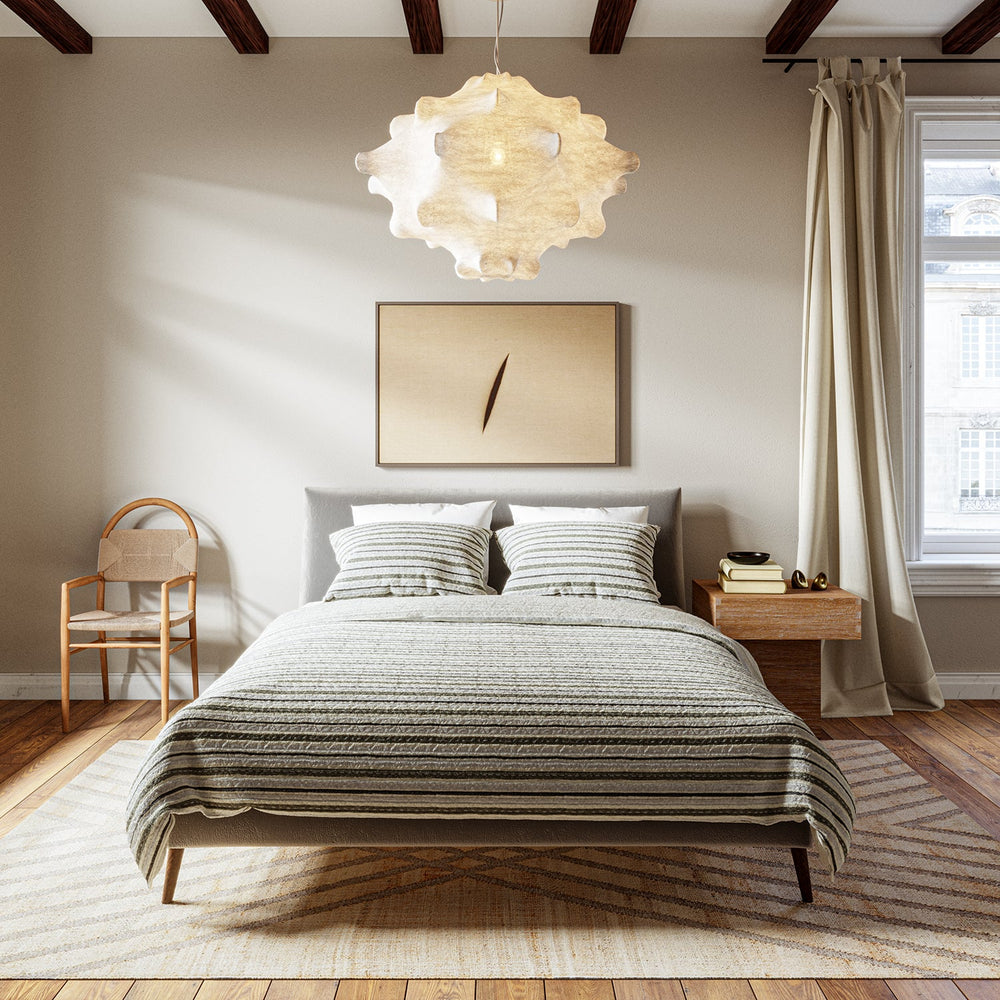 Lemieux et Cie Lucien Quilt Collection, hand-painted resist-dyed bedding in neutral striped pattern, styled in bedroom with wood floors and dark ceiling beams.