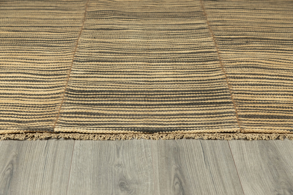 Lemieux et Cie Metlili rug in natural and charcoal striped handwoven wool, with antique wash finish and fringed edge, on pale wood flooring.