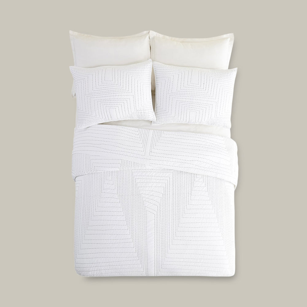 Lemieux et Cie Mondoro Quilt Collection in white cotton with geometric hand-drawn stitching, duvet and shams shown on neutral backdrop