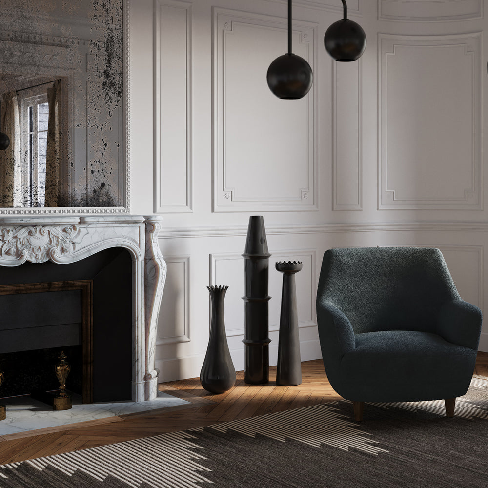 Lemieux et Cie Muguet Vase in black, sculptural decorative vase shown in a sitting room with paneled walls, carved marble mantel, and warm wood floors.
