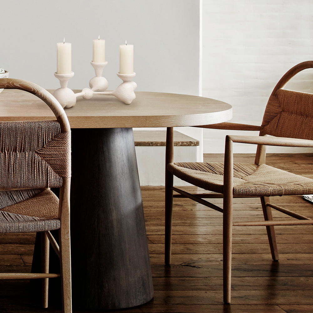 Lemieux et Cie Nunez Modern Candelabra, sculptural three-arm candelabra in warm ivory, displayed on a round dining table with woven chairs on wood flooring.